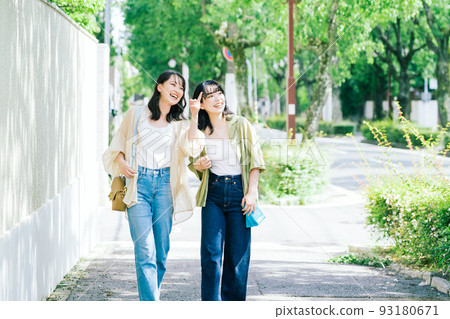 Female friends walking while chatting Female friends walking while chatting 93180671