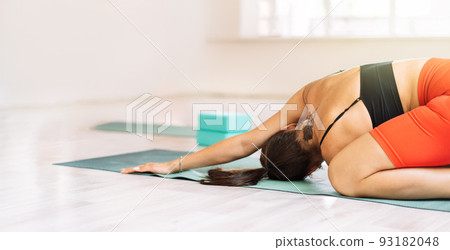 Girl on mat doing stretching in yoga class 93182048