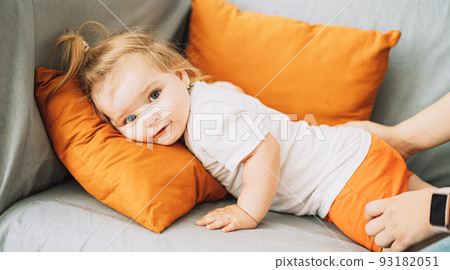 Female hands touching a little girl lying on a sofa Female hands touching a little girl lying on a sofa 93182051