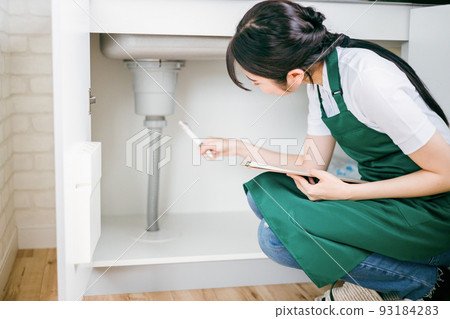 檢查供水的女性(在水槽下) 檢查供水的女性(在水槽下) 93184283