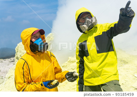 volcanologists on the slope of the volcano collect samples of minerals against the backdrop of smoking sulfur fumaroles volcanologists on the slope of the volcano collect samples of minerals against the backdrop of smoking sulfur fumaroles 93185459