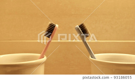 Used toothbrush placed in a glass in the bathroom. 93186055