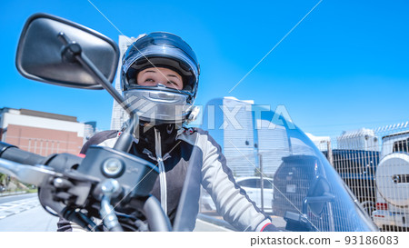 A smiling female rider touring Yokohama on a large American motorcycle 93186083
