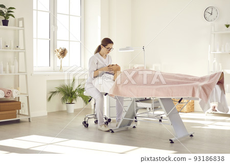 Female professional masseuse in beauty salon massages her face and head for her female client. Female professional masseuse in beauty salon massages her face and head for her female client. 93186838