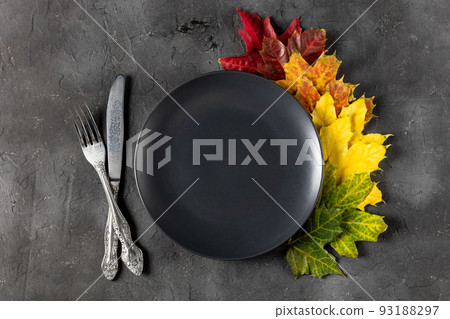 Autumn table setting with bright colorful leaves and black plate. Flat lay. 93188297