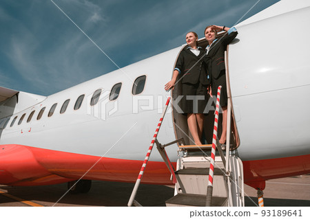 Two Women flight attendant standing on airplane stairs at airport and looking away before flight 93189641