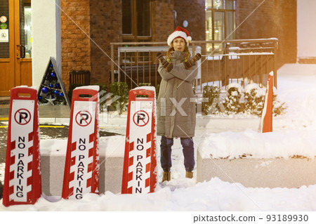 Woman showing forbidding gesture on the street. woman near sign in winter. No parking sign in winter. Woman in santa hat at evening in winter yard 93189930