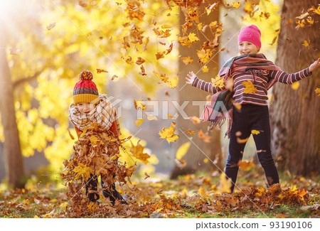 Children throwing colourful leaves in autumnal park 93190106