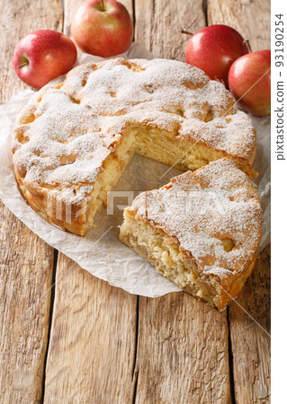 Homemade apple pie charlotte and piece of cake close-up on a parchment paper. Vertical 93190254