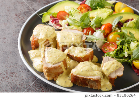 Pieces of tender pork tenderloin served with honey mustard sauce and lettuce, avocado and tomato salad close-up in a plate. Horizontal Pieces of tender pork tenderloin served with honey mustard sauce and lettuce, avocado and tomato salad close-up in a plate. Horizontal 93190264