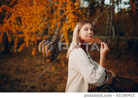 Happy active young woman riding bicycle in autumn park. Happy active young woman riding bicycle in autumn park. 93190453