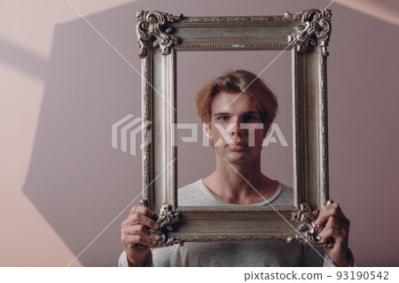 Millenial young man artist with blonde hair on gilded picture frame portrait. Millenial young man artist with blonde hair on gilded picture frame portrait. 93190542
