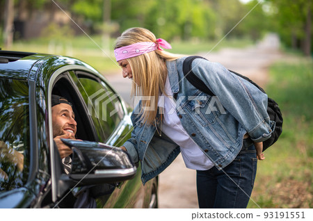 Blonde woman showing the way to a man in a car Blonde woman showing the way to a man in a car 93191551