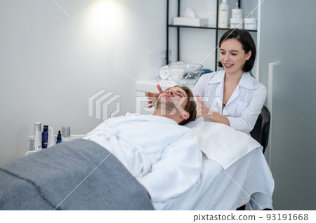 Young woman in lab coat working with a customer in a beauty salon 93191668