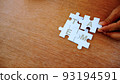 One hand put white jigsaw puzzle together. With wording of team. 93194591