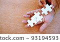 two hand put white jigsaw puzzle together on his hand. 93194593