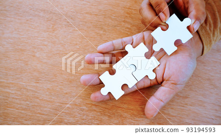 two hand put white jigsaw puzzle together on his hand. 93194593