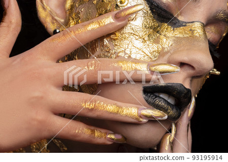 Beauty fashion model girl with golden make-up and body on black background. Golden body art. The golden face of a beautiful lady is touching. Artistic portrait. Beauty fashion model girl with golden make-up and body on black background. Golden body art. The golden face of a beautiful lady is touching. Artistic portrait. 93195914