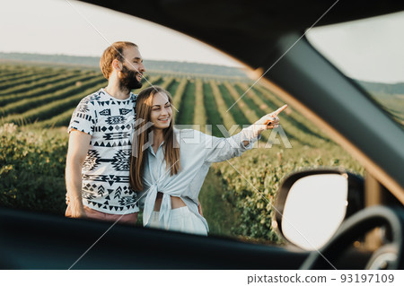 View through car window, happy middle-aged couple hugging together in the beautiful fields, caucasian man and woman enjoying vacation outdoors View through car window, happy middle-aged couple hugging together in the beautiful fields, caucasian man and woman enjoying vacation outdoors 93197109