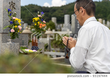 Senior man visiting a grave and putting his hands together 93197444