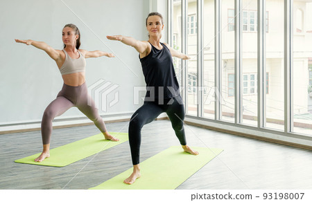 Two Caucasian women exercise doing the yoga pose stretching at home, healthy lifestyle concept Two Caucasian women exercise doing the yoga pose stretching at home, healthy lifestyle concept 93198007