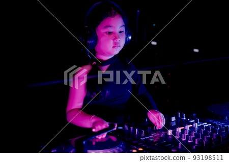 Asia little producer artist girl DJ in black headphones playing dance music and adjusting volume electronic sound mixer at the home party night Asia little producer artist girl DJ in black headphones playing dance music and adjusting volume electronic sound mixer at the home party night 93198511