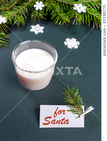 Milk glass for Santa Claus, Xmas tree branches and note with red inscription For Santa on turquoise background. Vertical orientation. Selective focus. 93198735