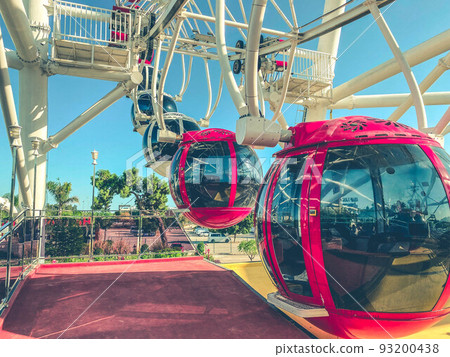 on the Ferris wheel there are large cabins for skiing tourists of red color with black, tinted windows to protect from the sun's rays. boarding tourists on the Ferris wheel there are large cabins for skiing tourists of red color with black, tinted windows to protect from the sun's rays. boarding tourists 93200438