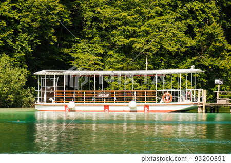 Excursion ship stands near the pier against green forest. Touristic attraction in natural park reserve on Plitvice lakes Excursion ship stands near the pier against green forest. Touristic attraction in natural park reserve on Plitvice lakes 93200891