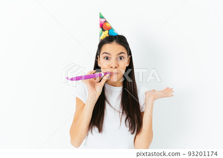 Cheerfully surprised young woman in festive birthday cap 93201174