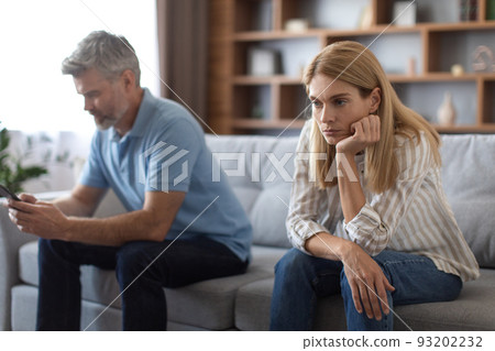 Offended upset mature caucasian female sad because husband have gadget addiction, guy plays smartphone 93202232