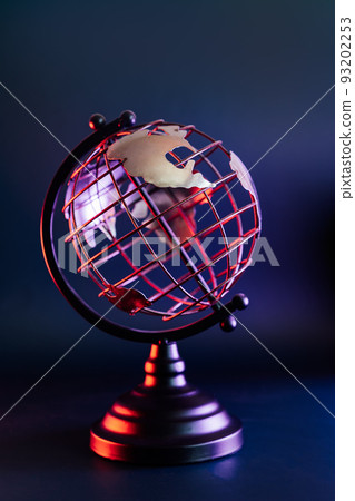 Close up metallic model of a globe with map in blue and red neon light. Bipolarity of the world. Geography concept. Vertical card. Selective focus, Copy space. 93202253