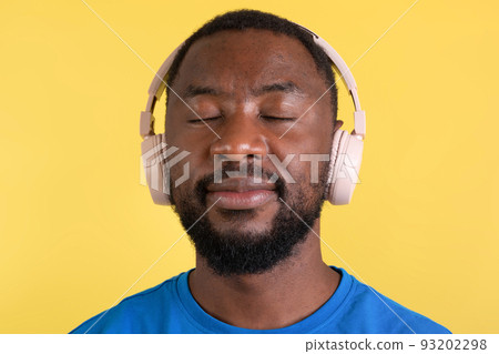 Portrait Of African Man Listening Music Wearing Headphones, Yellow Background 93202298