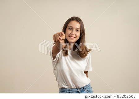 I choose you and command you. The smiling teenage girl pointing at camera, half-length close-up portrait on beige studio background. Human emotions, facial expression concept. Front view. I choose you and command you. The smiling teenage girl pointing at camera, half-length close-up portrait on beige studio background. Human emotions, facial expression concept. Front view. 93202505