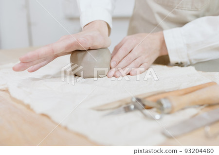 woman ceramist in the workshop makes mugs out of clay. small business or hobby is the creation of ceramic products woman ceramist in the workshop makes mugs out of clay. small business or hobby is the creation of ceramic products 93204480