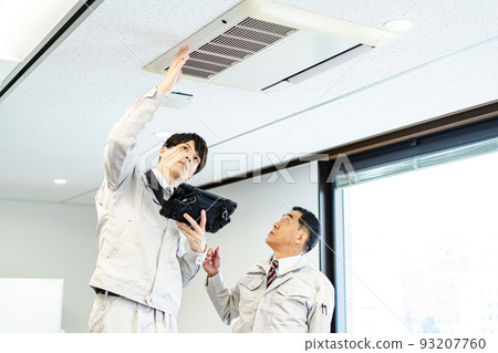 Two male workers inspecting the air conditioner 93207760