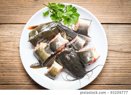 catfish fillet on white plate, fresh raw catfish menu freshwater fish, catfish for cooking food, fish chopped with ingredients coriander on wooden background catfish fillet on white plate, fresh raw catfish menu freshwater fish, catfish for cooking food, fish chopped with ingredients coriander on wooden background 93209777