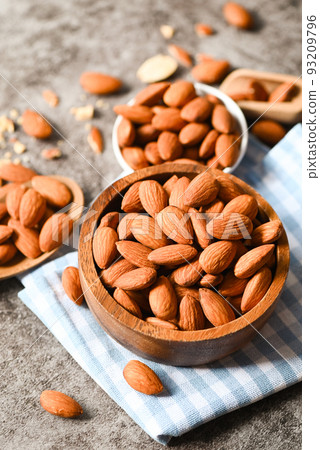 Almonds nuts on wooden bowl and dark background, Delicious sweet almonds on the table, roasted almond nut for healthy food and snack 93209796