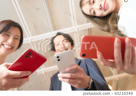 三個男人和女人把他們的智能手機拉近並微笑 93210349