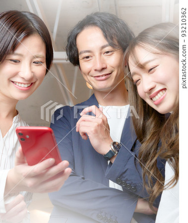 Three men and women laughing at the screen of the smartphone Three men and women laughing at the screen of the smartphone 93210362