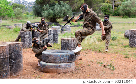 Two active opposing teams with guns playing paintball Two active opposing teams with guns playing paintball 93211044