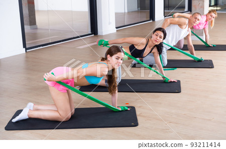 Active people perform a stretching exercise with the help of special rubber 93211414