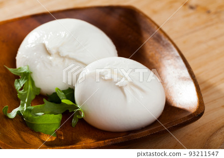 Burrata cheese and rukkola leaf closeup Burrata cheese and rukkola leaf closeup 93211547