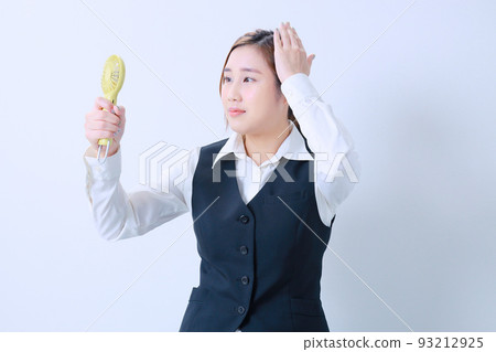 一位年輕的辦公室女士盯著一個方便的風扇 一位年輕的辦公室女士盯著一個方便的風扇 93212925