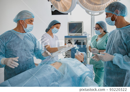 Concentrated surgical team working with patient in operation room. Withdrawal from anesthesia Concentrated surgical team working with patient in operation room. Withdrawal from anesthesia 93220322