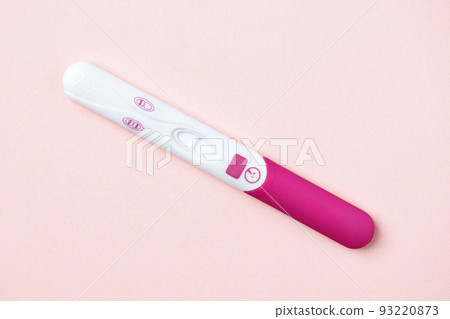 Pink positive pregnancy test on pink background. Positive result of pregnancy test. 93220873