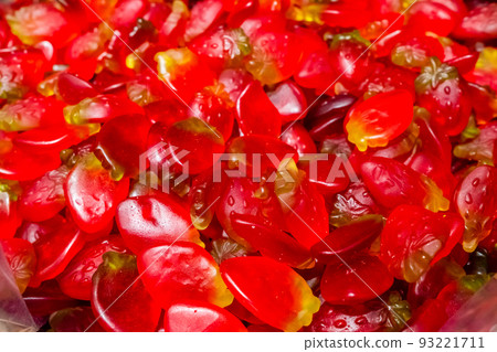 Bright red slices of marmalade chewing sweets. Sweet beautiful delicacy of gelled fruit juice. Bright colorful background. Randomly heaped goodies. 93221711