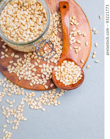 Flat lay. Glass jar with Siberian cedar nuts standing on a wooden stand.  93221773