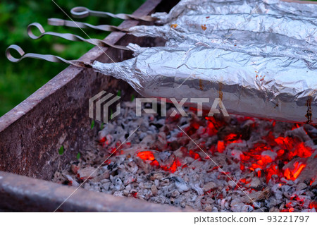 The meat on metal skewers is wrapped in aluminum foil and grilled on charcoal. The meat on metal skewers is wrapped in aluminum foil and grilled on charcoal. 93221797