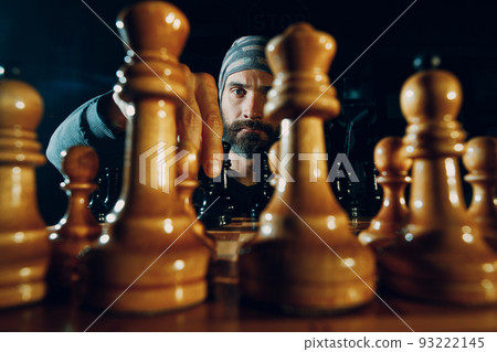 Young adult handsome man playing chess in dark. Chess figures and male face on board. 93222145